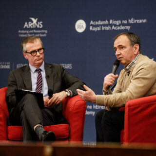 Closeup of Pat Fenlon speaking to Colin Graham on stage.