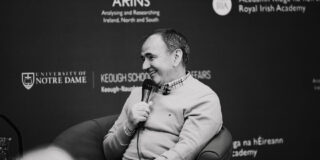 Black and white photo of Pat Fenlon sitting onstage at the ARINS event.