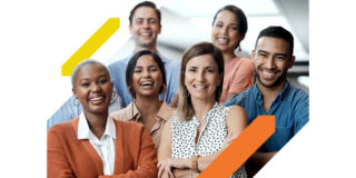 A group of six people, ethnically and gender-diverse, all smiling in front of a bright background posing to this one-quarter headshot